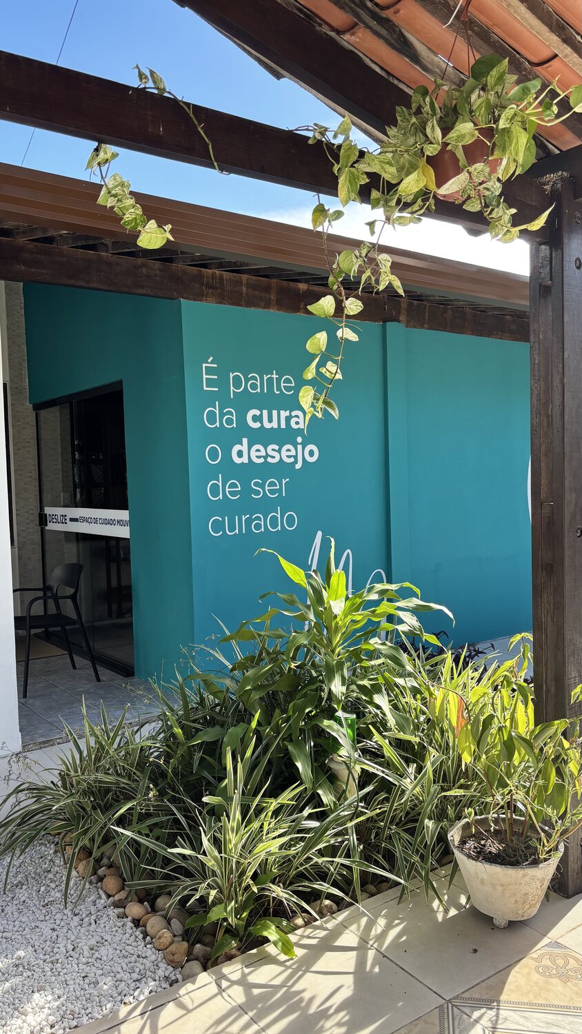 Entrada do estúdio com jardim e parede azul-turquesa