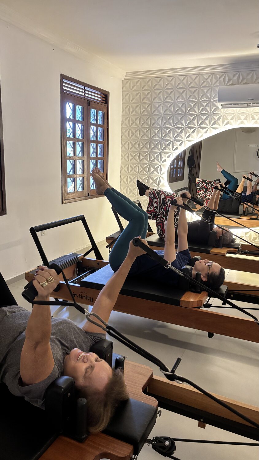 Três alunas em exercício sobre reformers no estúdio